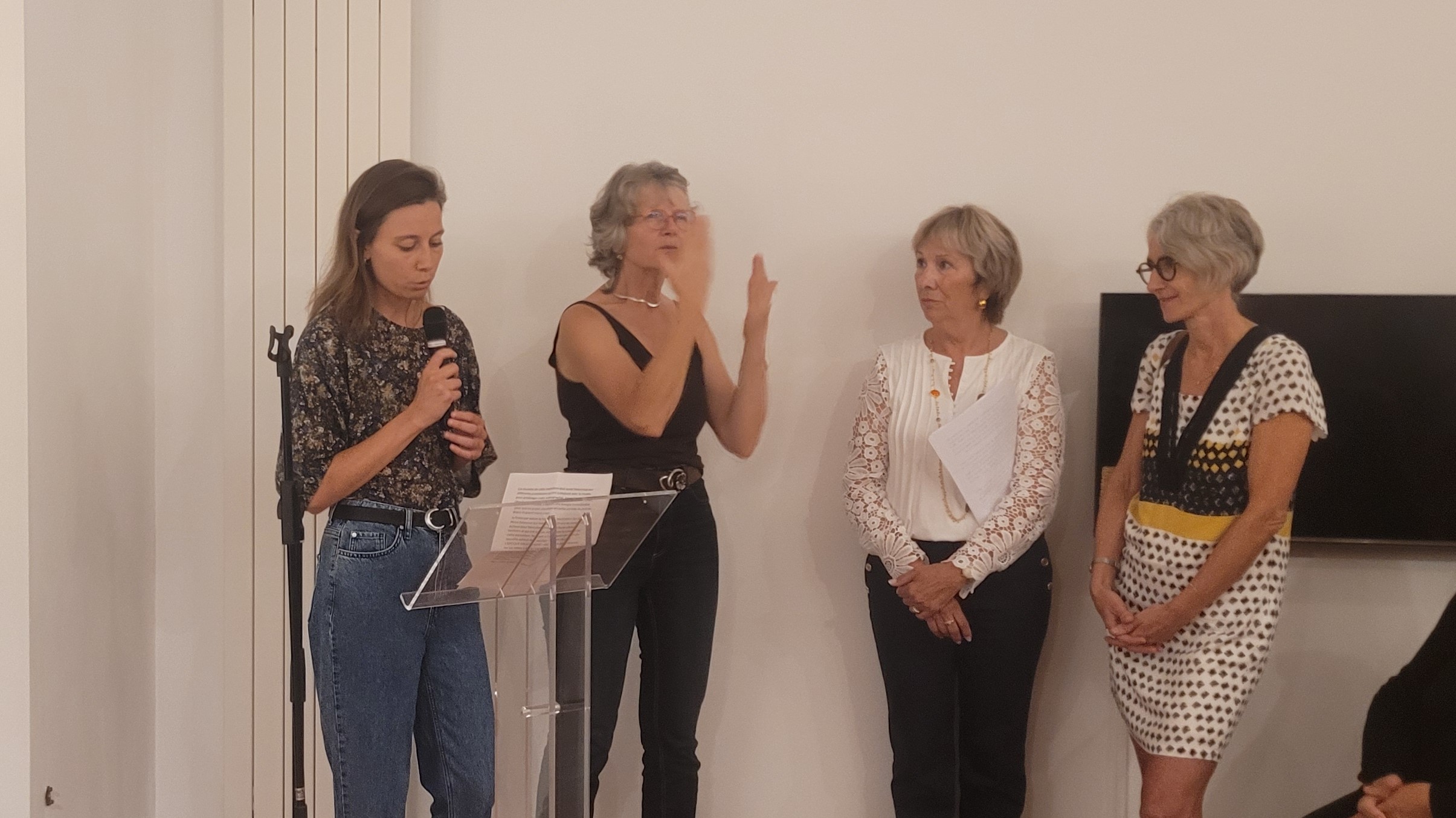 Discours d'ouverture d'Agathe Frochot. A sa droite, une interprète LSF signe le discours. Avec un haut blanc, Bernadette Saudemont.