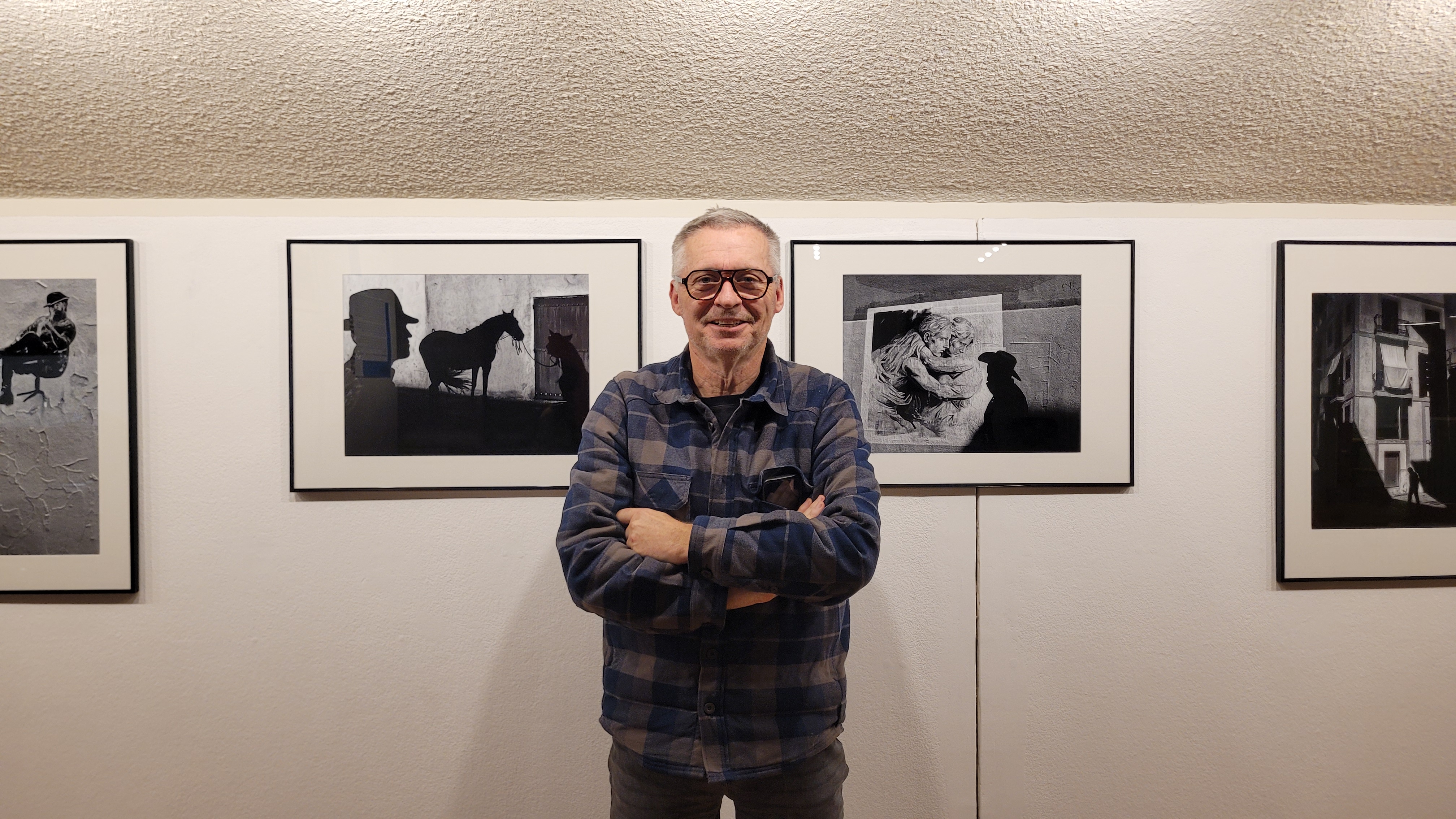 Olivier Chomis dans la galerie de l'Entre-sort, devant quelques uns de ses tirages